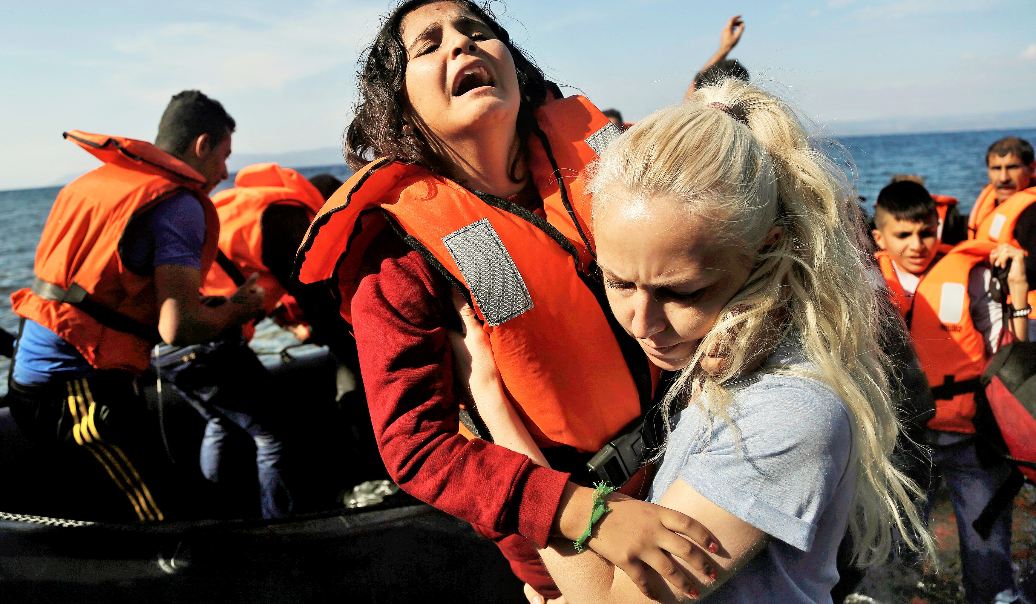 A Syrian girl reacts as she helped by a volunteer upon her Oct. 9 arrival from Turkey to the Greek island of Lesbos. Greece is bracing for thousands more Syrian and other migrants to land on Lesbos and other key island crossings from Turkey, as those fleeing conflict remain undeterred by the worsening weather and colder autumn temperatures. (CNS photo/Yannis Kolesidis, EPA) See GREECE-MIGRANTS-HELP Oct. 13, 2015.