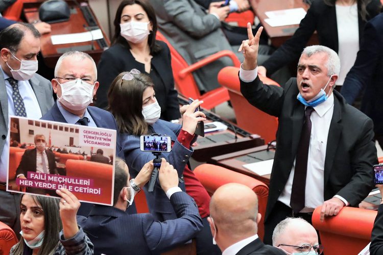 Turkish member of Parliament for the left wing political party Peoples' Democratic Party Omer Faruk Gergerlioglu (C) reacts as he is surrounded by MPs applauding and brandishing placards after he was dismissed following a vote at the Turkish Parliament in Ankara, on March 17, 2021. (Photo by Adem ALTAN / AFP)